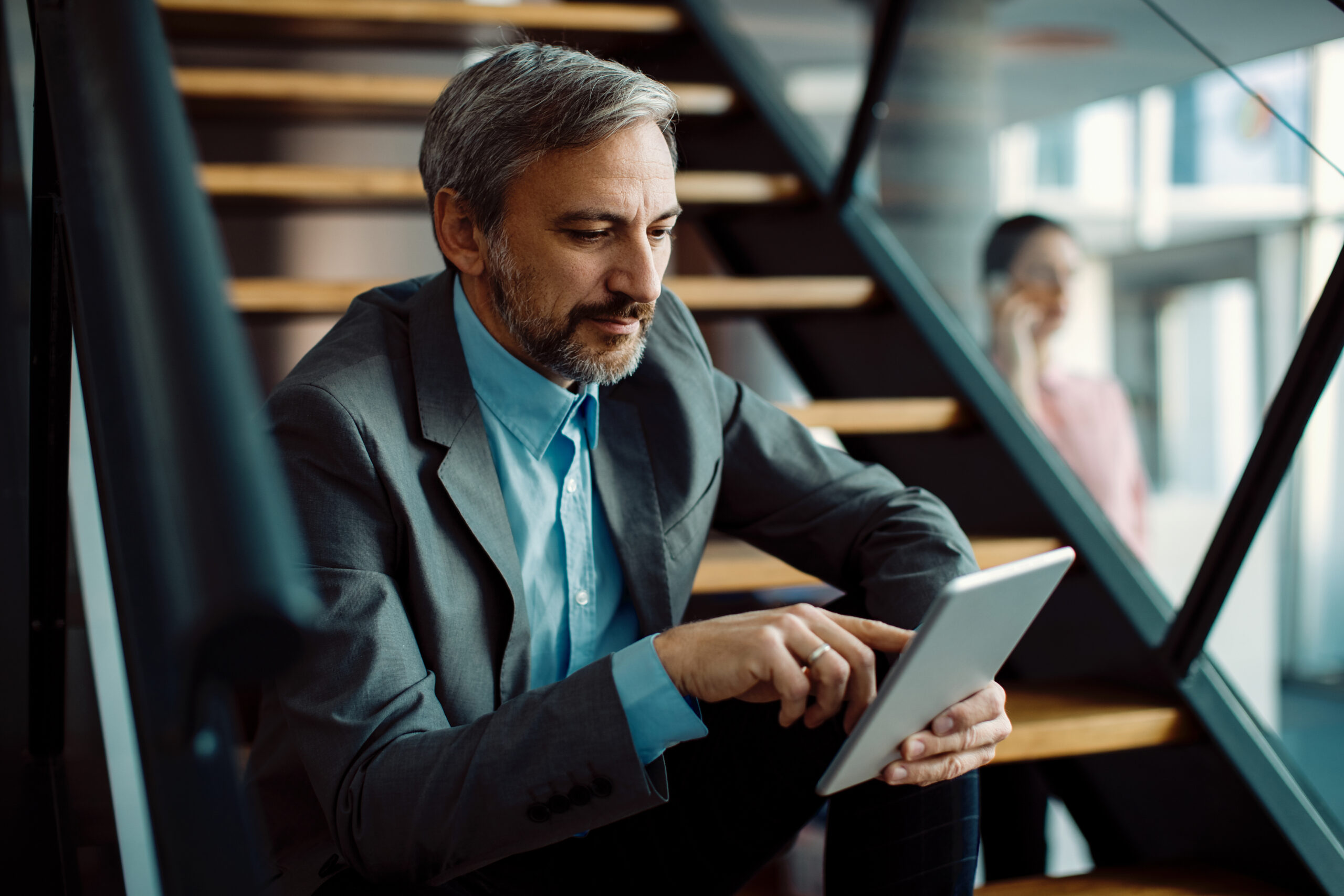 Male entrepreneur using digital tablet while sitting on staircas